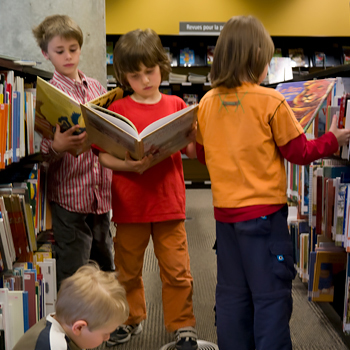 Un groupe d'enfant lit dans l'Espace Jeunes de la Grande Bibliothèque.