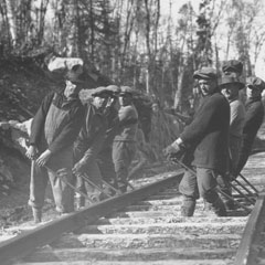 Hommes en train de poser des rails de chemin de fer.