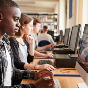 Un jeune homme, les mains sur le clavier, semble concentré face à son ordinateur.