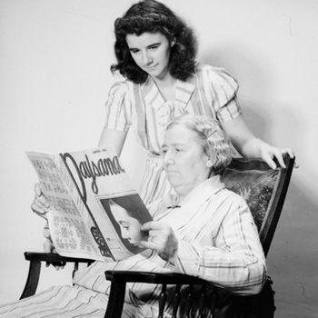 Madame Arthur Poirier lit la revue «Paysana». Sa fille Lilian lit par-dessus son épaule.