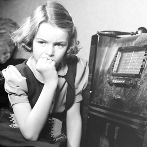 Jeune fille à côté d'une radio antique.